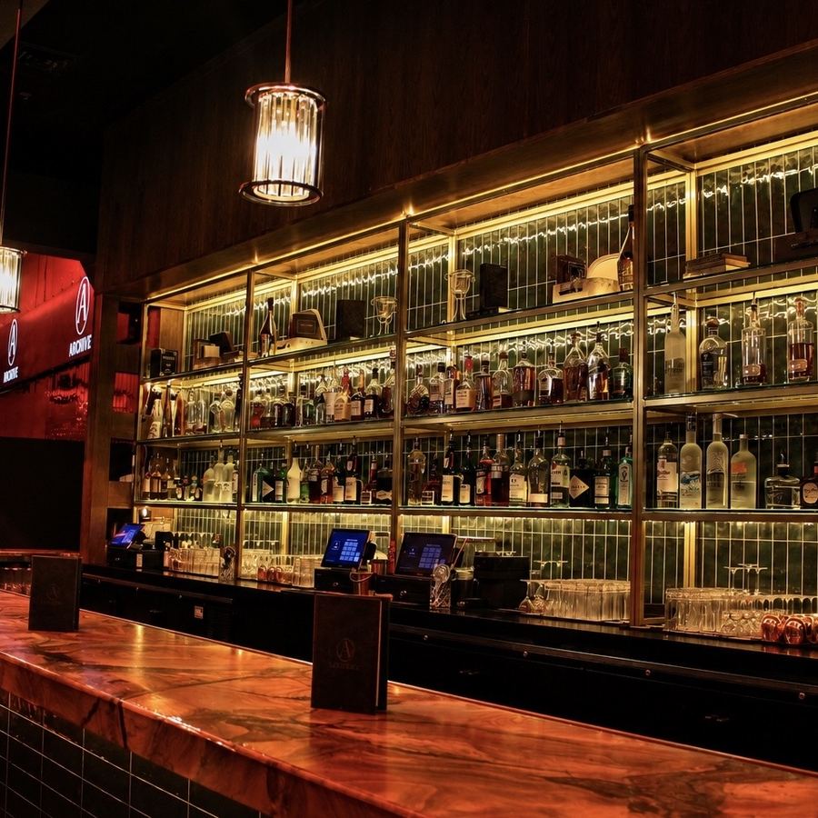 The backlit bar at Archive Sacramento, lined with bottles above a polished counter
